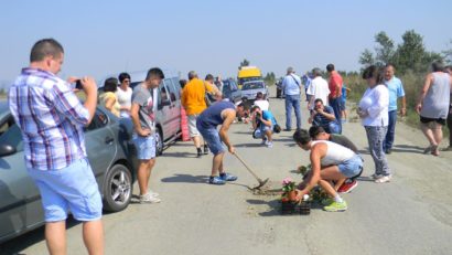 FOTO / Protest față de ‘tranșeele’ din drum. Zeci de oameni au plantat flori în gropile din asfalt